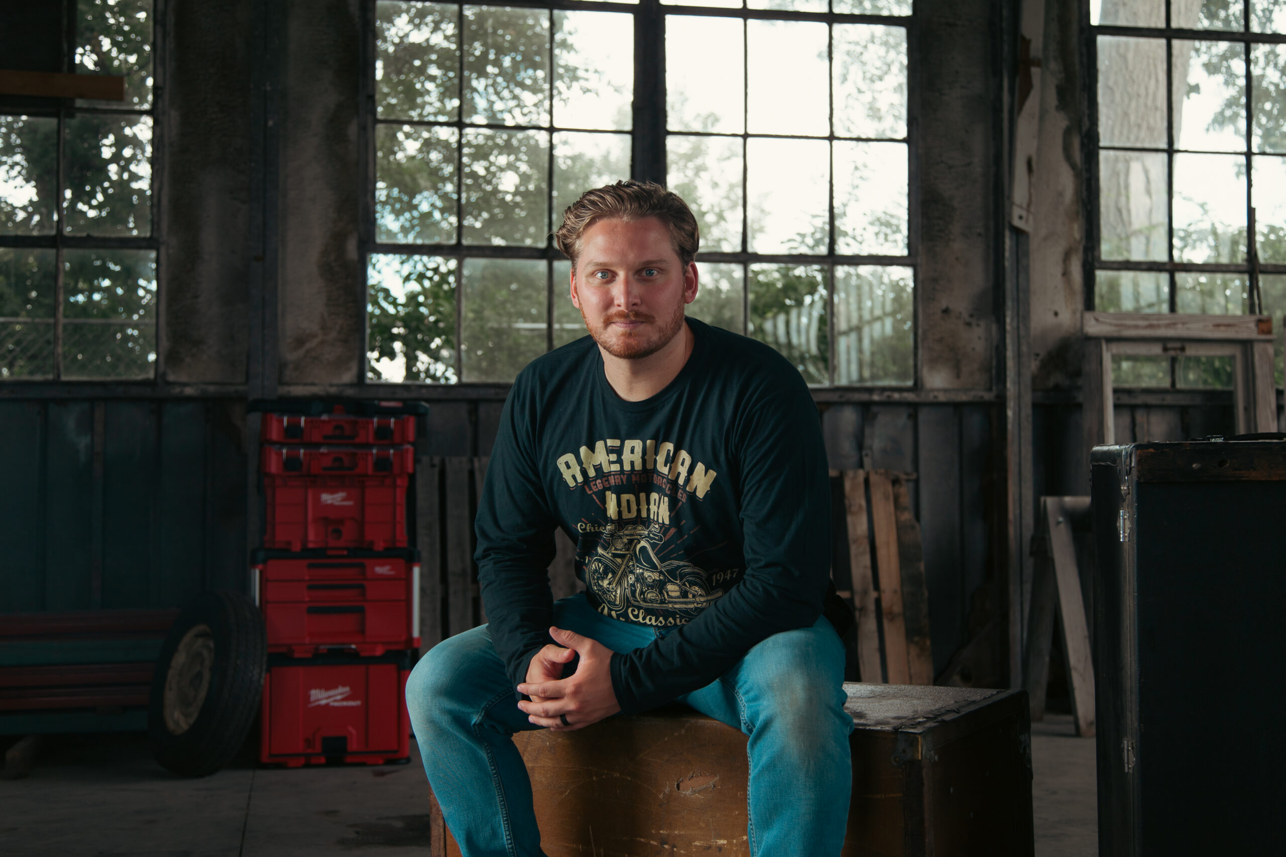 Ryan leaning on a blue V8 engine block in a workshop